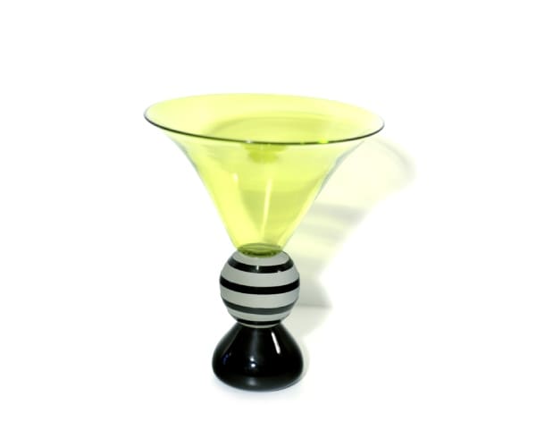 A yellow glass bowl with black and white striped base.