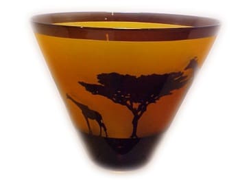 A glass vase with giraffes and trees on it.