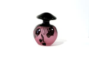 A pink and black glass bottle with a lid.