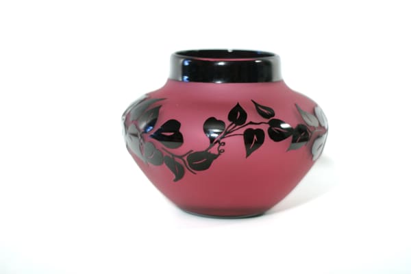 A red vase with black leaves on it.
