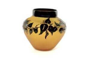 A vase with black leaves on it