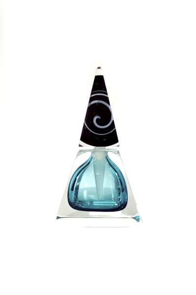A blue glass bottle with black swirl on top of it.