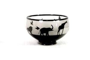 A bowl with animals on it and birds in the background.