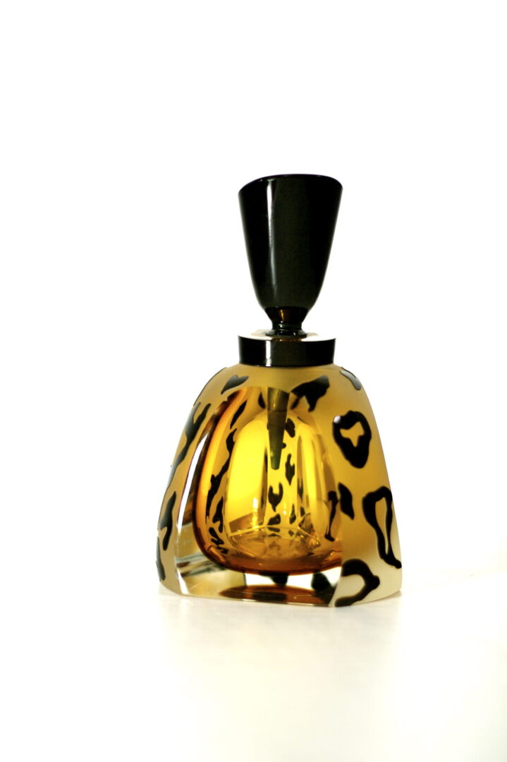 A leopard print glass bottle with black top.