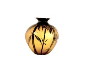 A vase with black and gold design on it.