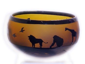 A bowl with animals on it and birds flying around.