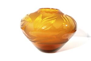 A close up of an orange vase with leaves