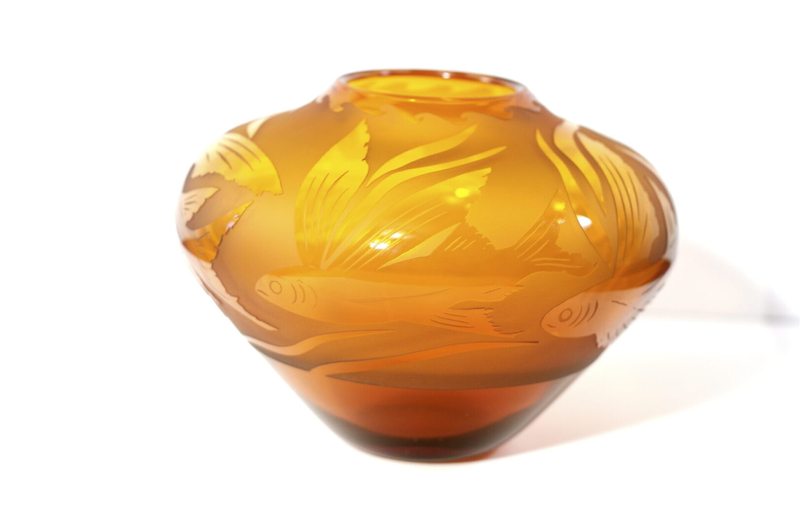 A close up of an orange vase with leaves