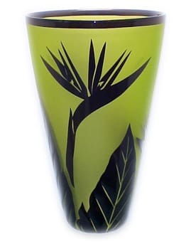 A green vase with black flowers and leaves.