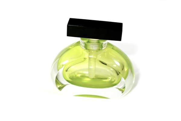 A green bottle of perfume sitting on top of a table.
