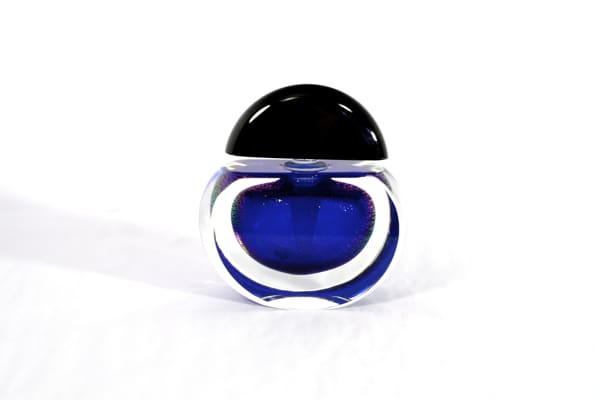 A blue glass container with black lid on top of white surface.