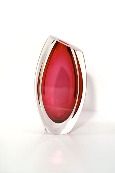 A red glass vase sitting on top of a table.